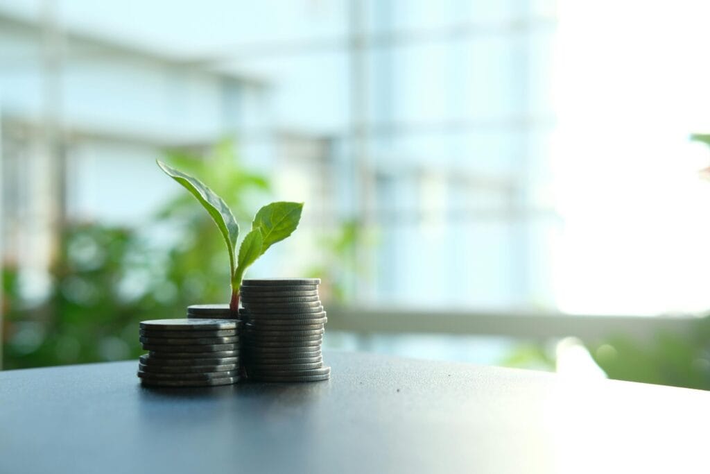 coins on a table with a plant growing through them to represent how money grows with investing