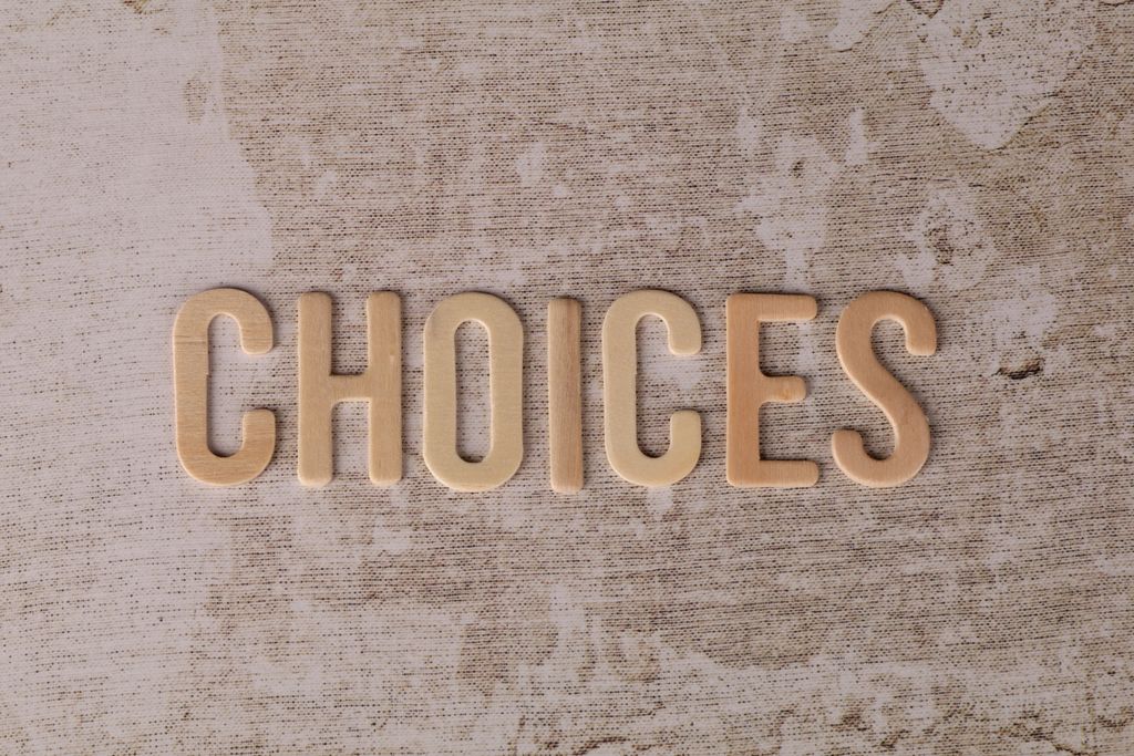 Wooden letters spelling 'choices' on a textured surface, symbolizing decision-making.